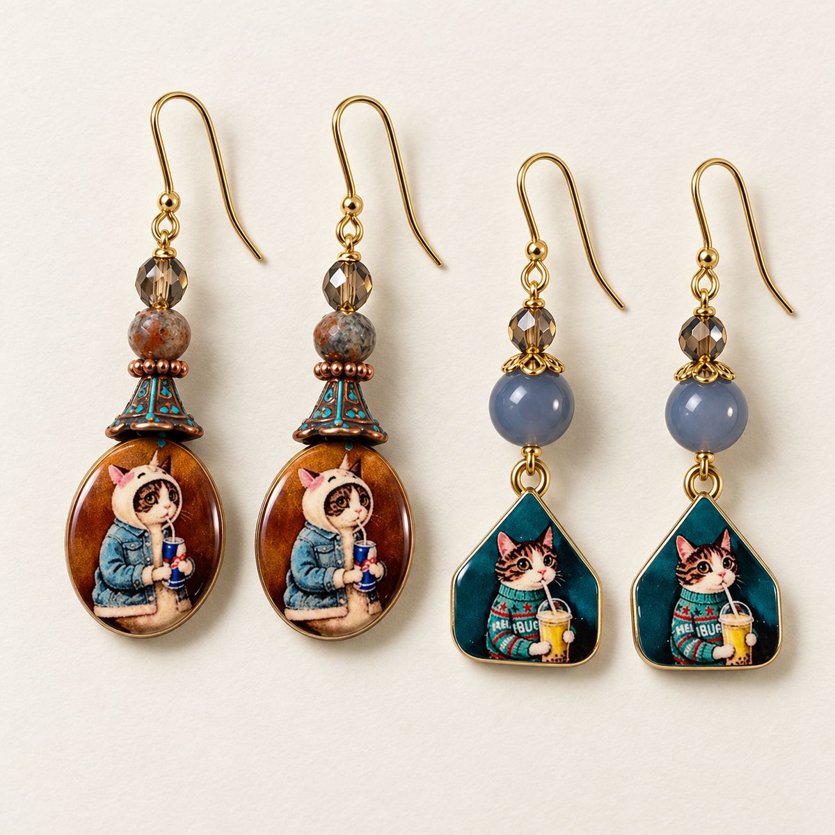 Two pairs of cat dangle earrings: brown oval drops with a hooded kitten and teal geometric drops with a sweater-wearing kitten, both with beaded accents.


