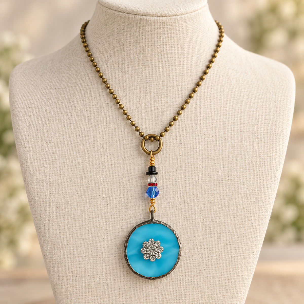 Blue stained glass necklace with a sparkling snowflake detail and a tiny beaded snowman above the pendant on an antique-tone ball chain.